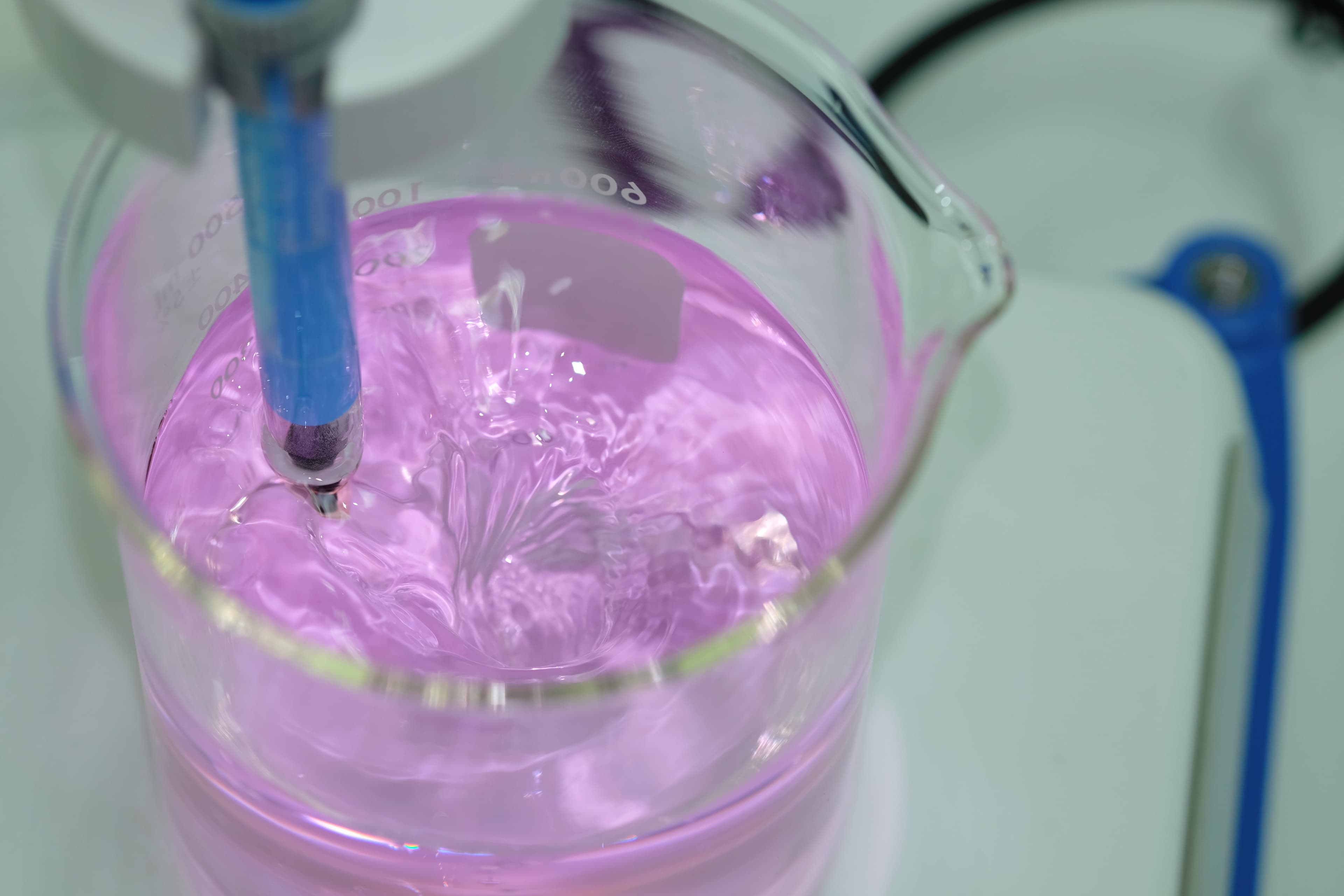 Pipette mixing a vibrant beverage formula in a beaker